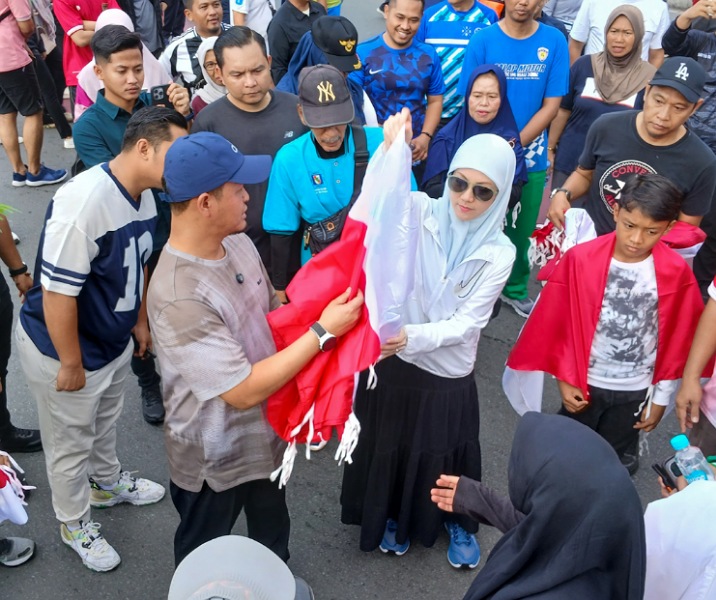 Walin Kota Pekanbaru Agung Nugroho bersama istrinya, Sulastri, saat membagikan bendera Merah Putih di Bundaran Zapin, Minggu (3/8/2025). Foto: Surya/Riau1.