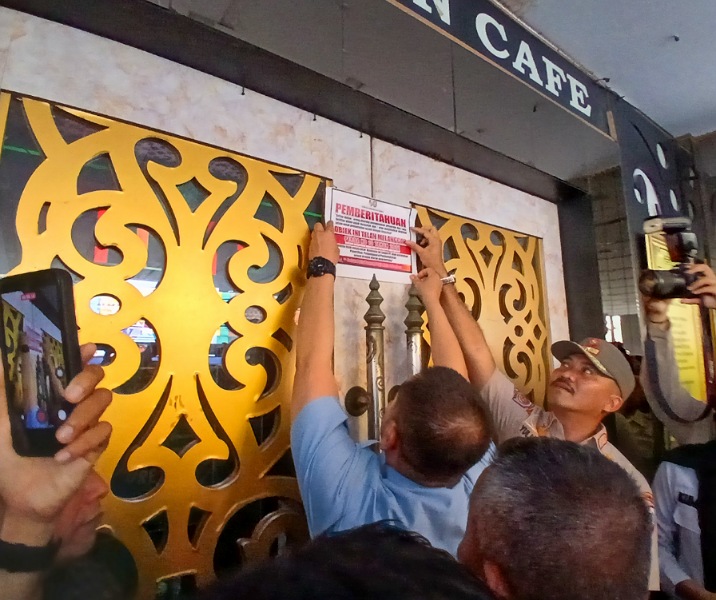 Petugas Satpol PP Pekanbaru memasang segel di pintu depan tempat hiburan malam Paragon, Selasa (3/2/2026). Foto: Surya/Riau1.