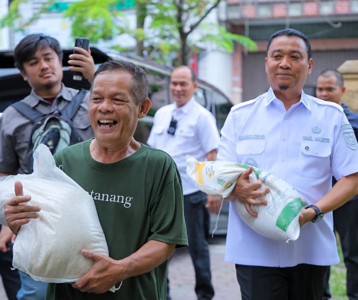 Warga Kecamatan Pekanbaru Kota semringah menerima bantuan 2 karung beras dari pemerintah. Wawako Markarius Anwar membantu warga mengangkut beras. Foto: Istimewa.
